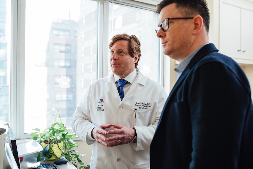 Picture of doctor and businessman by window.